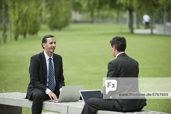 Geschäftsleute diskutieren über die Arbeit bei der Nutzung von Laptops im Freien
