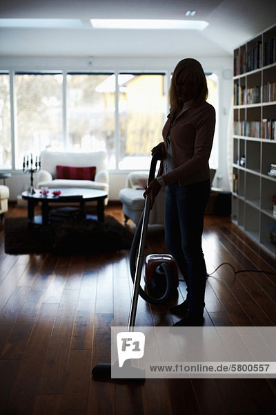 Frau saugt Wohnzimmerboden ab
