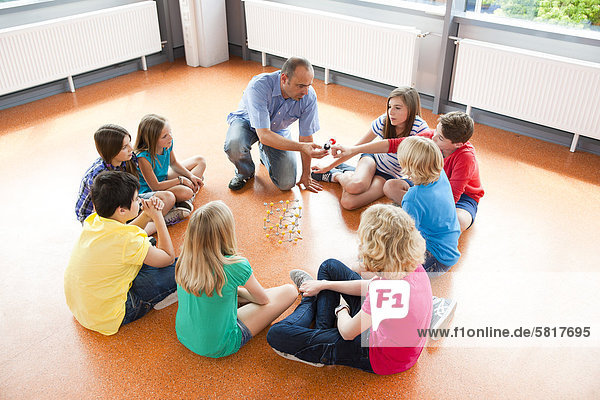 Schüler und Lehrer sitzen im Kreis zusammen