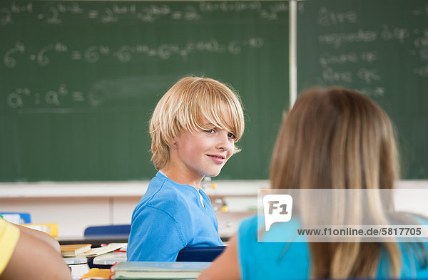 Lächelnder Schüler im Klassenzimmer dreht sich um