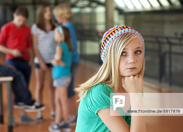 Ernste Teenagerin vor einer Gruppe von Schulkindern
