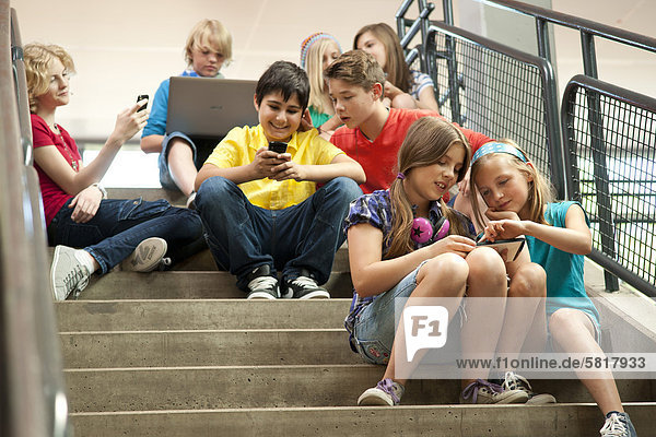 Schoolchildren using wireless technology on stairs