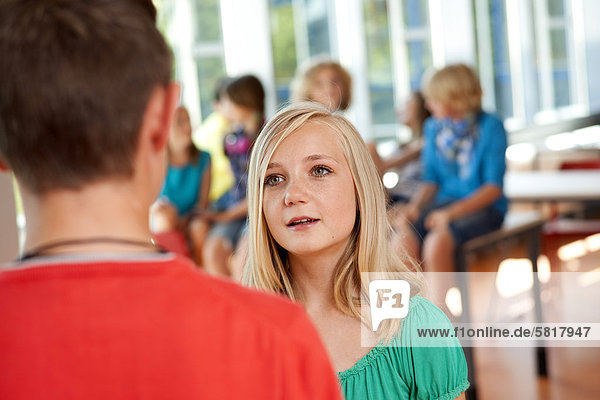 Teenage girl looking seriously at teenage boy in school