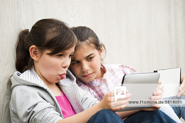Zwei Mädchen mit einem Tablet PC machen Grimassen