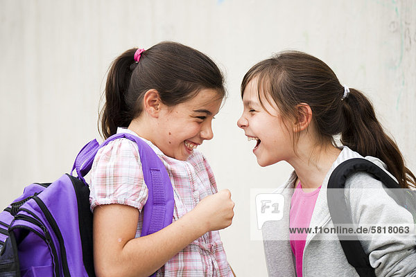Zwei lachende Mädchen schauen sich an