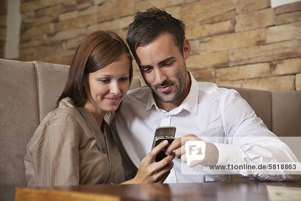 junges Paar Freigabenachricht auf Handy im restaurant