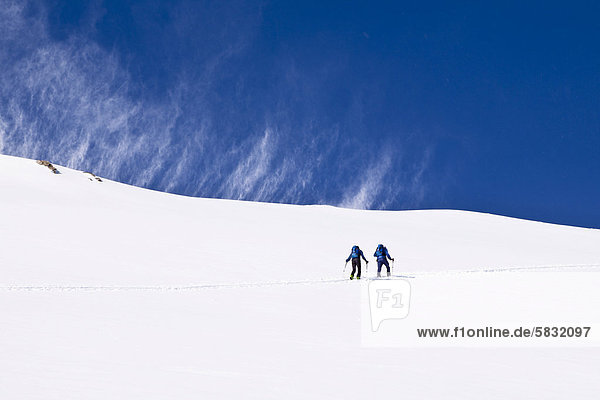 Two backcountry skiers  chinook wind  Zischgelesspitze mountain  Zischgeles mountain  Stubai Alps  Tyrol  Austria  Europe