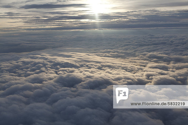 Wolkendecke vom Flugzeug aus  mit Sonnenlicht auf einem Teil der Wolken