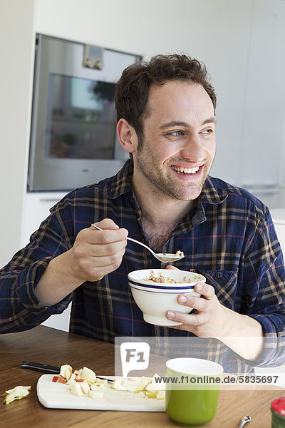 Smiling man eating bowl of cereal