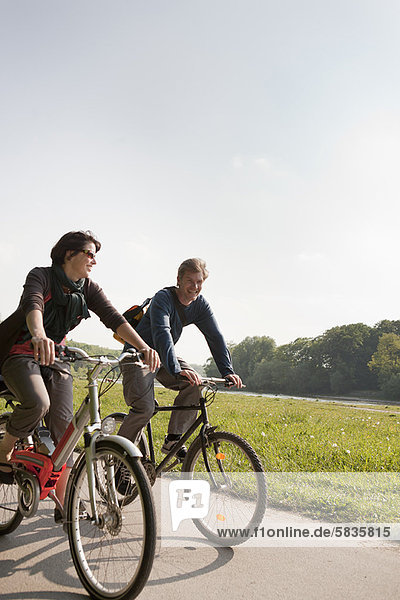 Couple riding bicycles on rural road