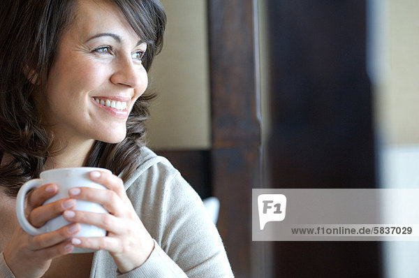 Lächelnde Frau bei einer Tasse Kaffee