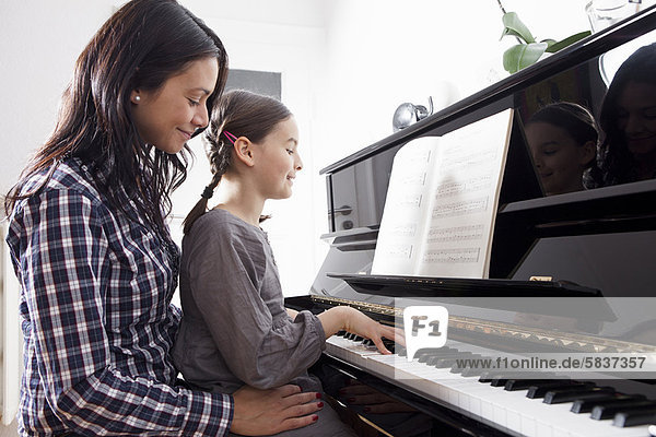 Mutter und Tochter am Klavier sitzend