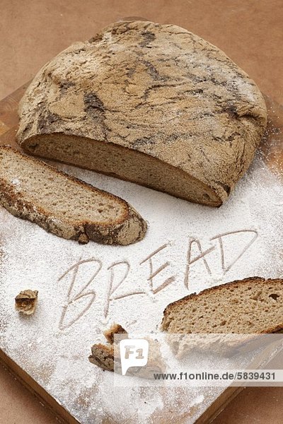 Country bread  sliced and the word BREAD written in flour