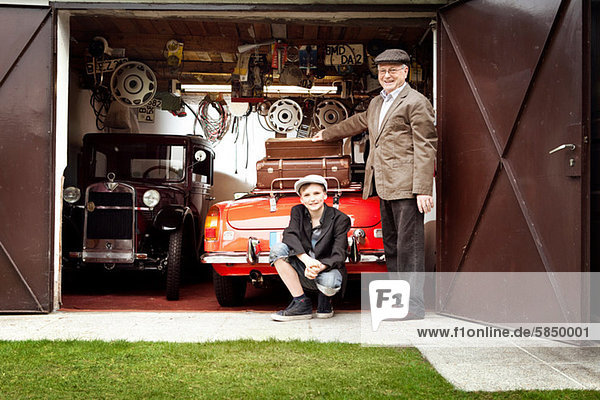 Großvater und Enkel mit Oldtimer und Koffer in der Garage