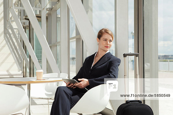 Geschäftsfrau am Flughafen sitzend mit digitalem Tablett  Portrait