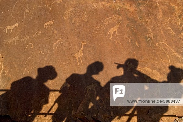 Schatten von Touristen auf Felsgravuren Weltkulturerbe Twyfelfontein Uibasen Conservancy Damaraland Namibia