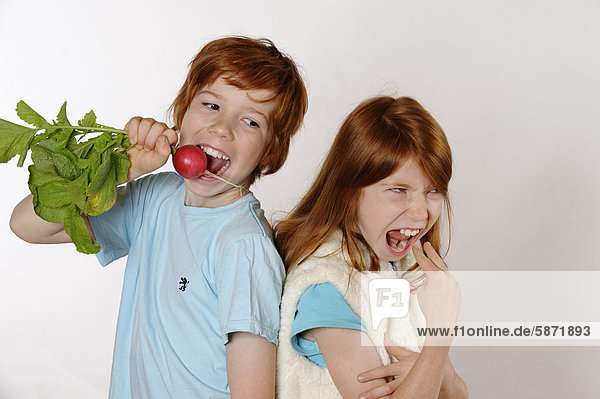 Boy eating radishes  girl rejecting raw food or vegetables