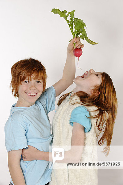 Boy feeding a radish to a girl