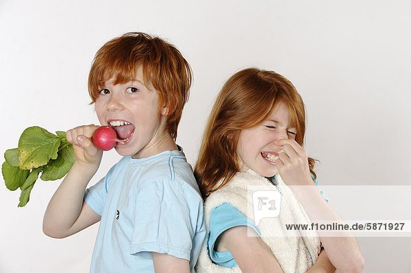 Boy eating radishes  girl rejecting raw food or vegetables