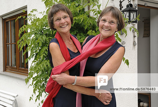 Zwei rüstige Zwillingsschwestern  gleich gekleidet mit roten Schals