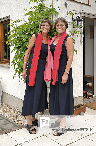 Zwei rüstige Zwillingsschwestern  gleich gekleidet mit roten Schals