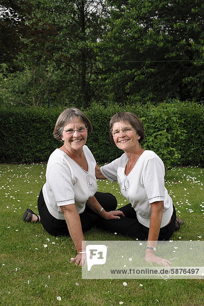 Zwei rüstige Zwillingsschwestern sitzen im Garten