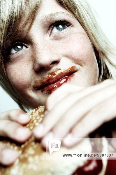 Close_up of a boy holding a burger