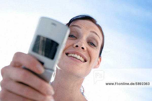 Portrait of a young woman smiling and holding a mobile phone
