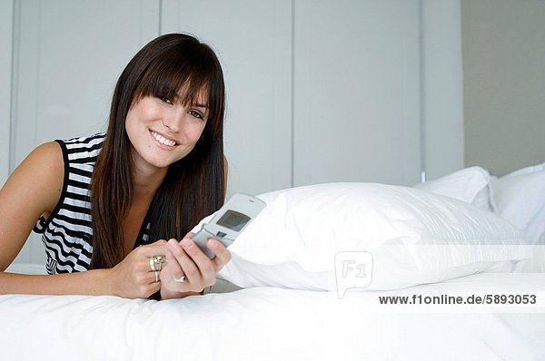 Handy Portrait Frau lächeln halten Bett Kurznachricht jung