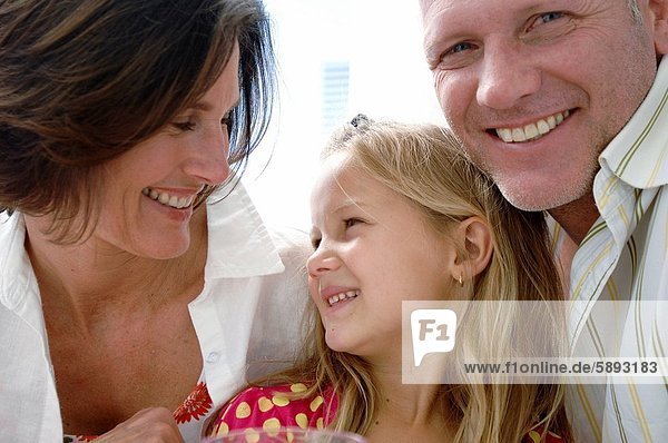 Close_up of a mid adult couple and their daughter smiling