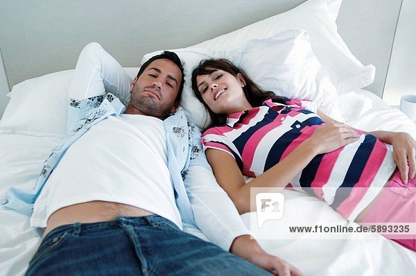 Erhöhte Ansicht eines jungen Paares auf dem Bett liegend