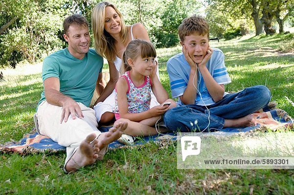 Mid adult couple sitting with their two children in a park