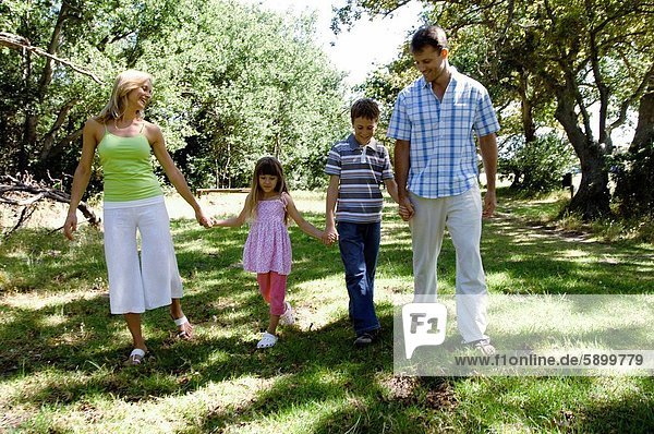 Mid adult couple walking with their two children in a park