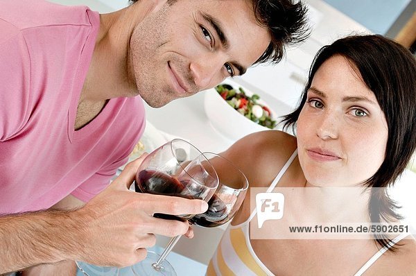 Close_up of a young couple toasting with wine glasses at the kitchen counter