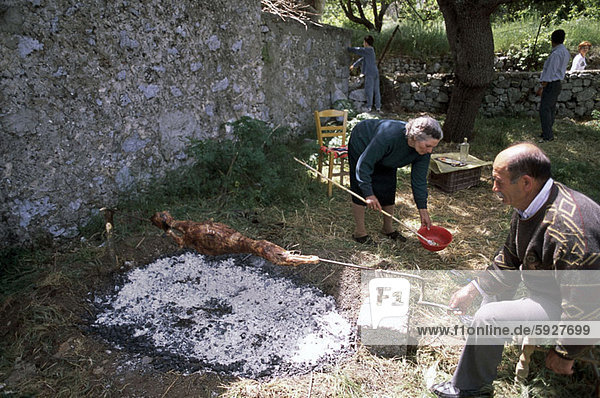 Side profile of a senior man roasting meat on a spit  Crete  Greece
