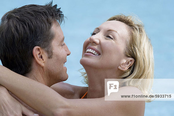 Close-up of a mid adult couple embracing each other in a swimming pool. Close-up of a mid adult couple embracing each other in a swimming pool