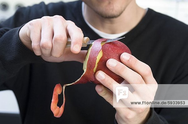 Mid section view of a man peeling an apple with a knife. Mid section view of a man peeling an apple with a knife