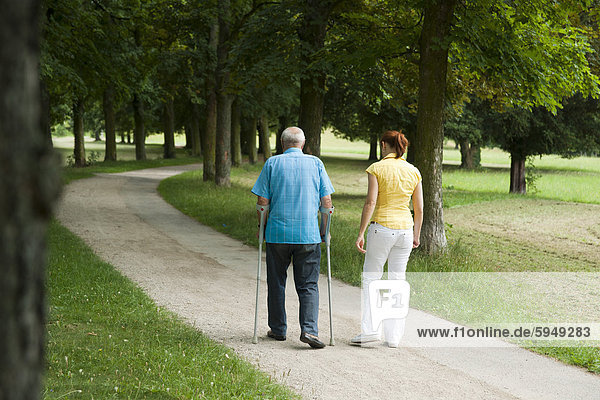 Woman walking with old man in park