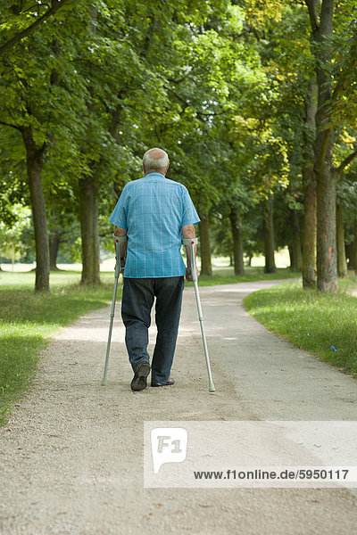 Alter Mann geht in einem Park spazieren