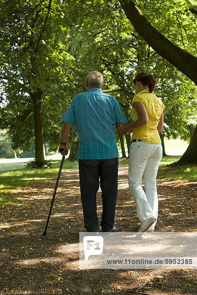Frau geht mit einem alten Mann im Park
