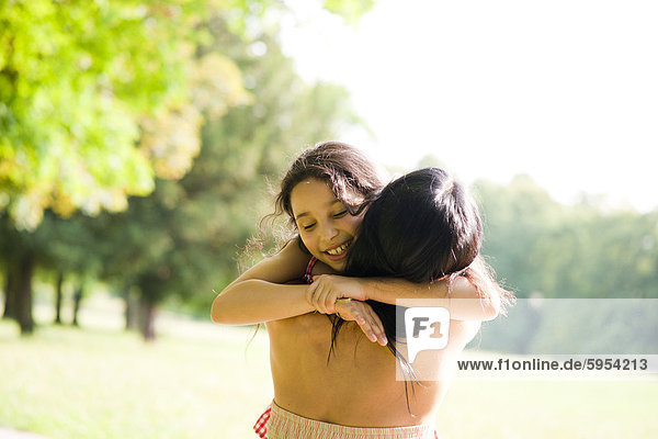 Mutter und Tochter umarmen sich in einem Park