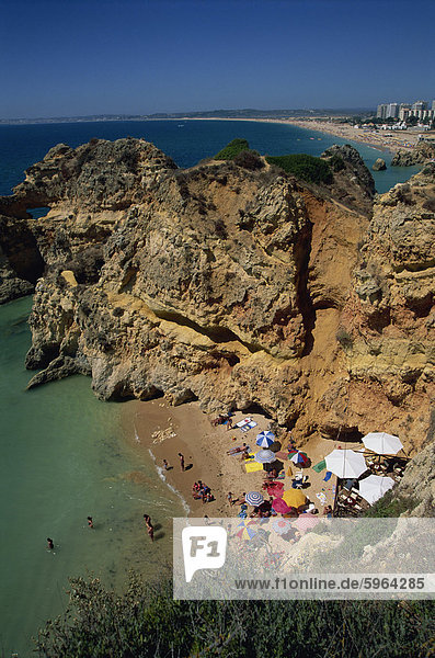 Aerial view of tourists on a small beach or cove on the rocky coast at Praia de Rocha in the Algarve  Portugal  Europe
