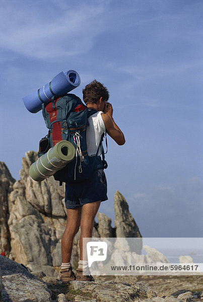 Porträt der hinteren Ansicht des Backpacker mit Bettzeug  Brötchen und Rucksack auf der Insel Ouessant in Bretagne  Frankreich  Europa