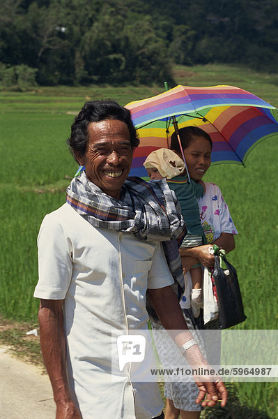 Porträt einer Familie  Mutter  Vater und Kind  den Mann lächelnd und Blick auf die Kamera  ein Spaziergang durch ein Reisfeld  Toraja Region  Sulawesi  Indonesien  Südostasien  Asien