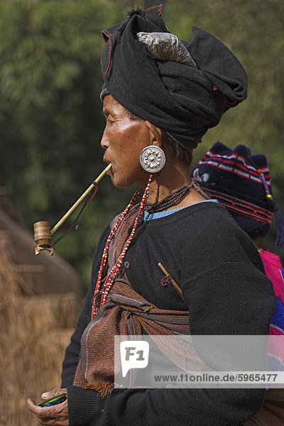 Aku lady with baby on her back smoking wooden pipe  Wan Sai village  Kengtung (Kyaing Tong)  Shan state  Myanmar (Burma)  Asia