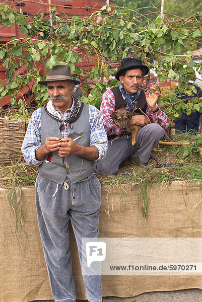 Two men in traditional costume  one holding a dog  at the annual Autumn Wine and Food Parade  Asti  Piedmont  Italy  Europe