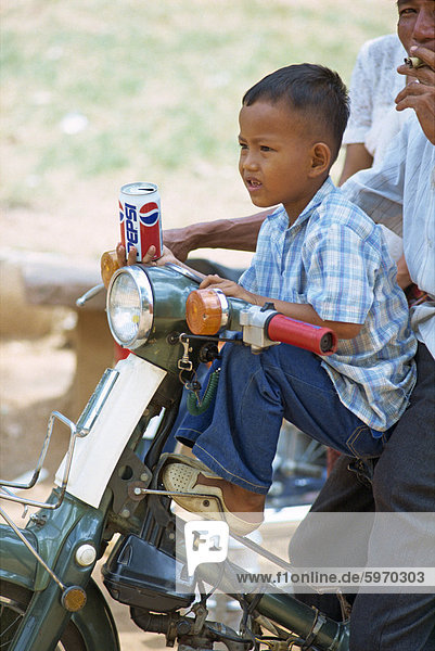 Portrait of a small boy holding a can of Pepsi  on a motorcycle in Phnom Penh  Cambodia  Indochina  Southeast Asia  Asia