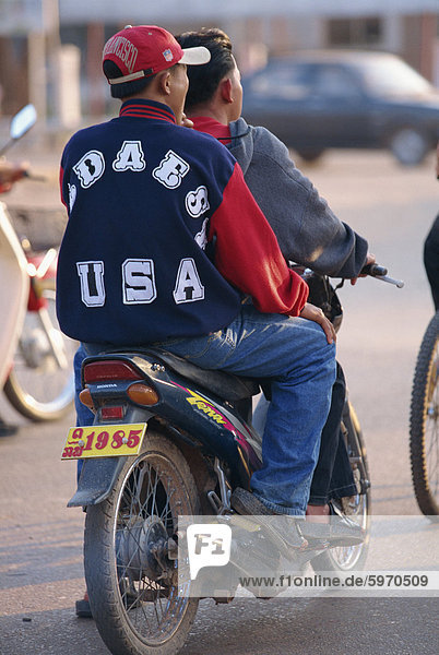 Young boy in western clothes  denims and baseball cap on the back of a motorcycle in Vientiane  Laos  Indochina  Southeast Asia  Asia