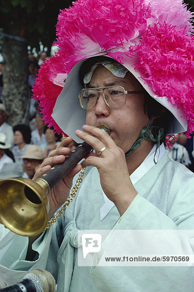 Portrait of a musician in a pink hat blowing an instrument during the Farmers Dance in Haewundae Park in Pusan City  South Korea  Asia