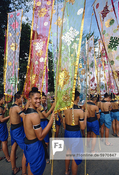 Porträt eines lächelnden Menschen in einer Parade von bunten Fahnen während des Festivals von Loy Krathong in Sukhothai  Thailand  Südostasien  Asien